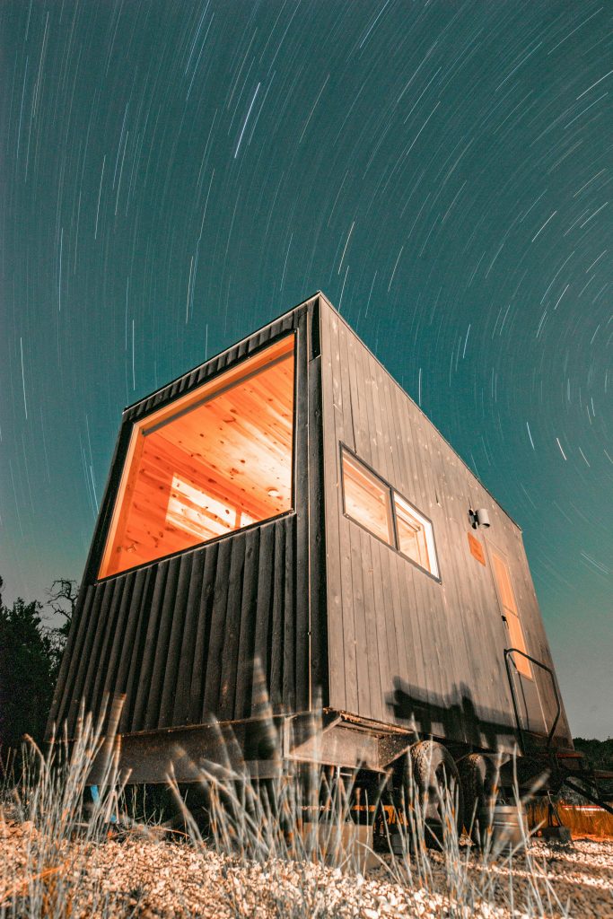 pexels-photo-5872466-5872466 Night view of a modern tiny house illuminated under a starry sky in Wimberley, Texas.