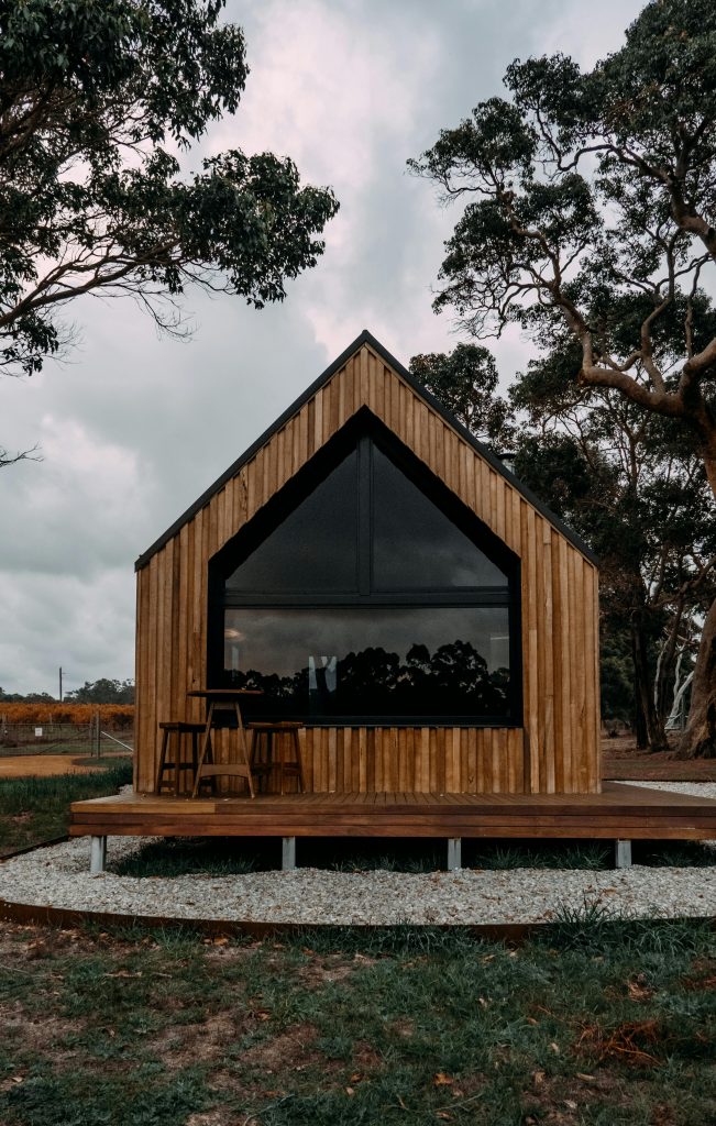 pexels-photo-8112838-8112838 A contemporary wooden cabin in a rural outdoor setting surrounded by tall trees.